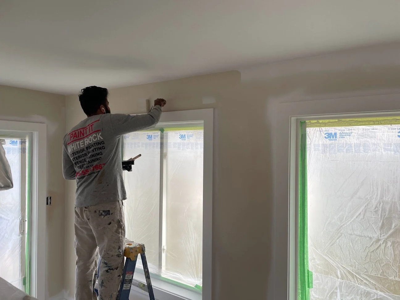 After masking off the windows, doors and floor we sprayed the ceiling and then the trim, and now we are painting the walls!