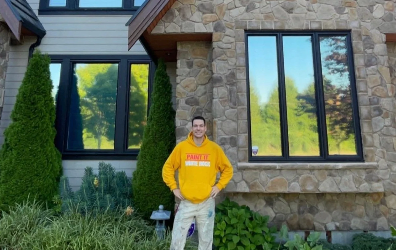 Expert Paint It White Rock employee proudly standing in front of a beautifully painted home exterior, showcasing high-quality craftsmanship and attention to detail.