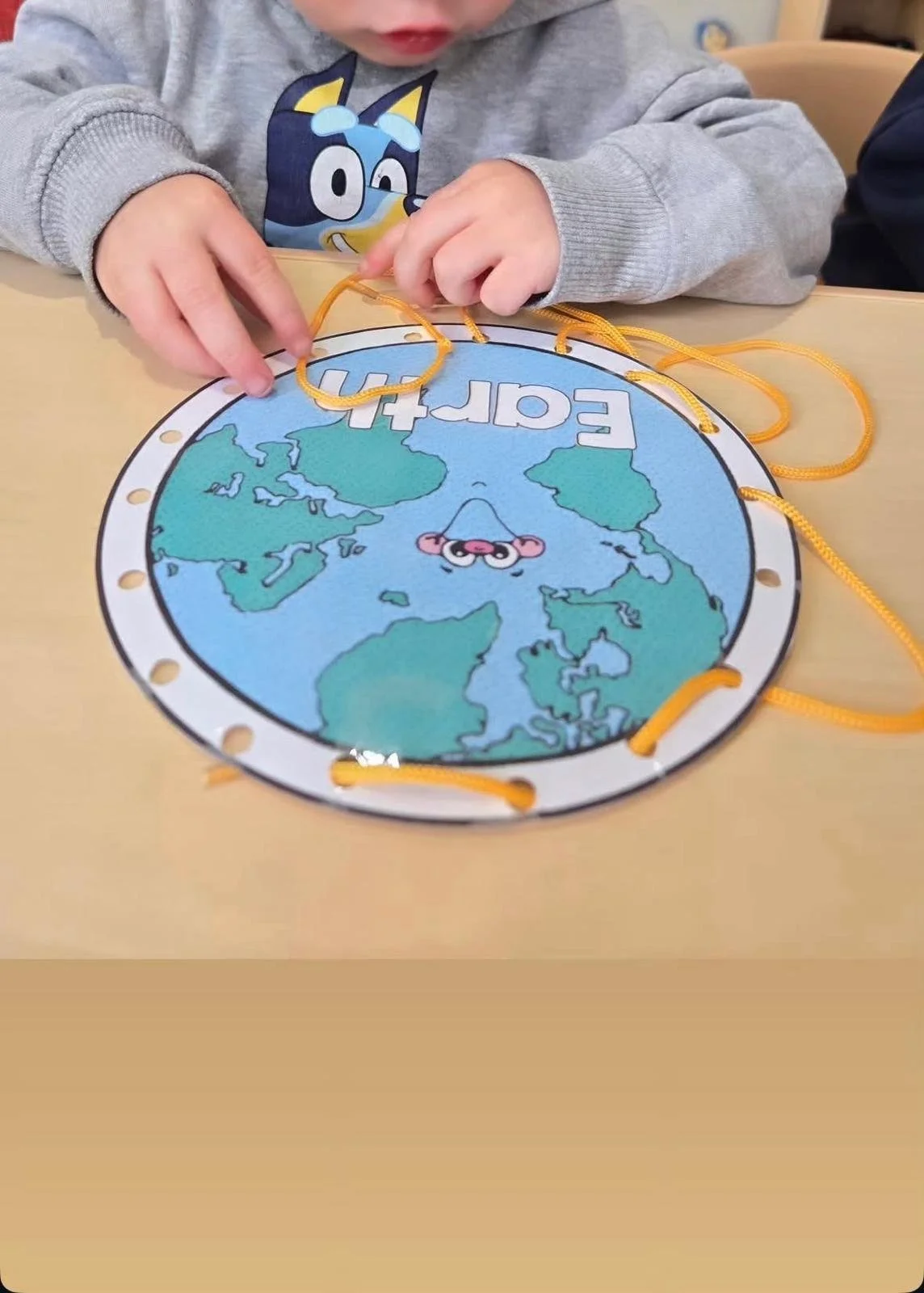 A young child leaning at the little learning center in Norwalk, CT. The toy has a map of the world and the word 'Earth' visible.