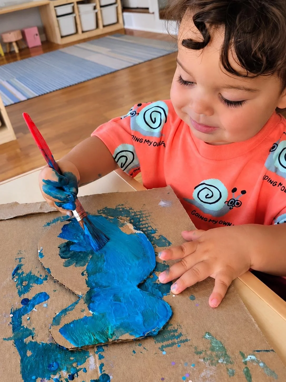 A young boy painting blue on a cardboard cutout of a butterfly with a paintbrush in a classroom at the little learning center in Norwalk, CT.