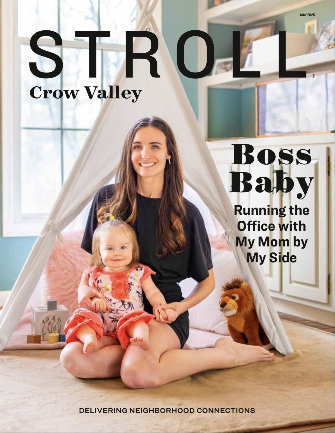 Cover of a magazine titled 'STROLL Crow Valley Boss Baby Running the Office with My Mom by My Side,' featuring a woman and a young girl sitting inside a teepee in a cozy, well-lit room with large windows, shelves, and framed pictures. The woman is smiling and the girl is sitting on her lap, with a stuffed lion toy beside them.