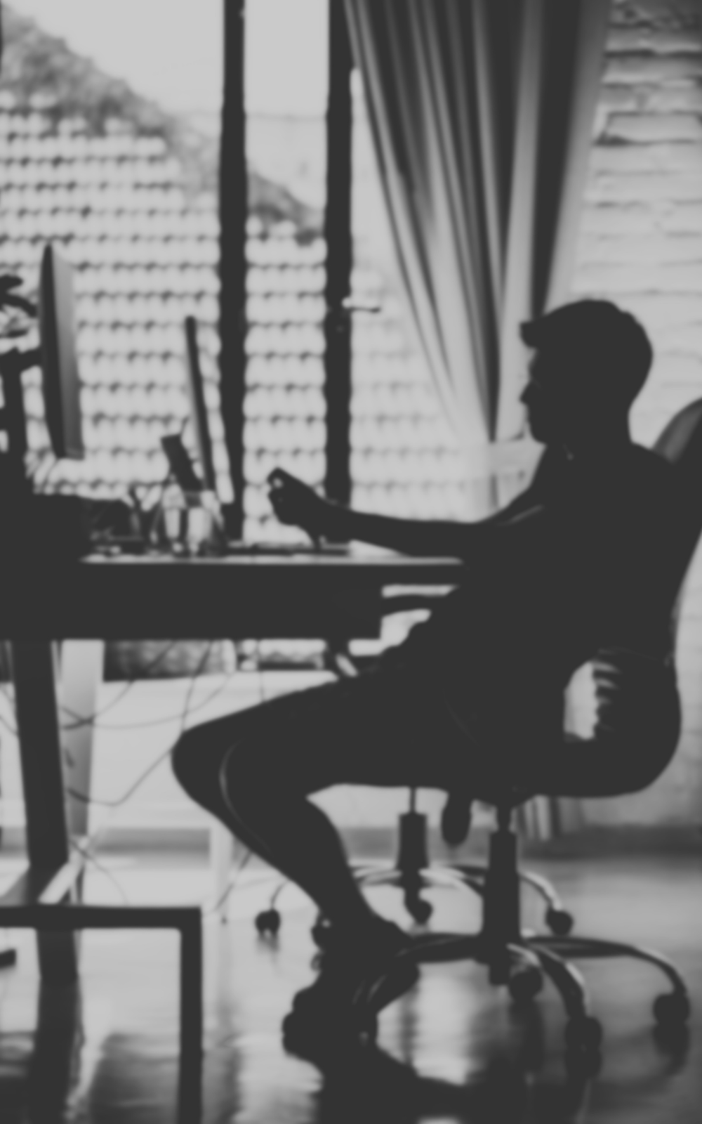 Black and white image of a man working in his home office