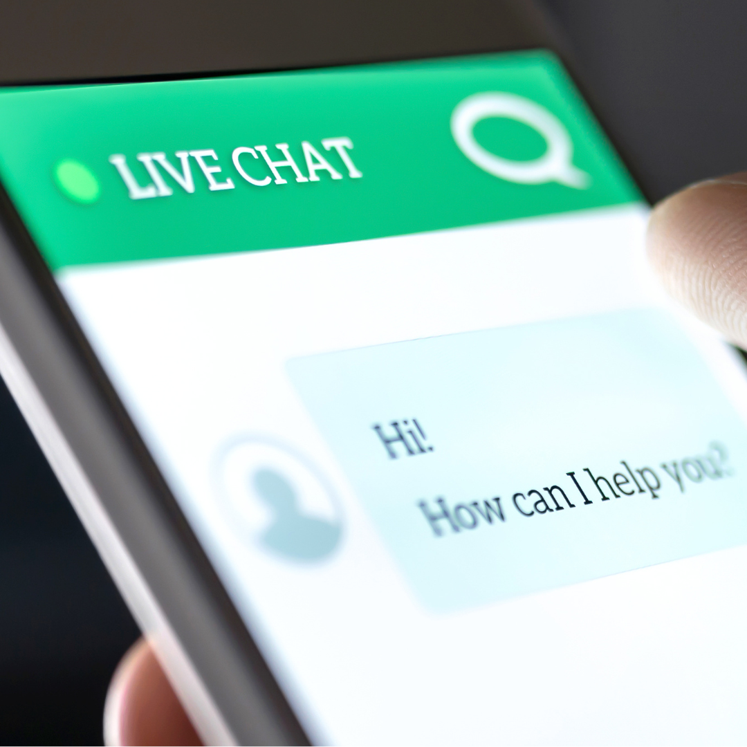 Close-up of a smartphone screen showing a chat app with the words 'LIVE CHAT' at the top and a message saying 'Hi! How can I help you?'