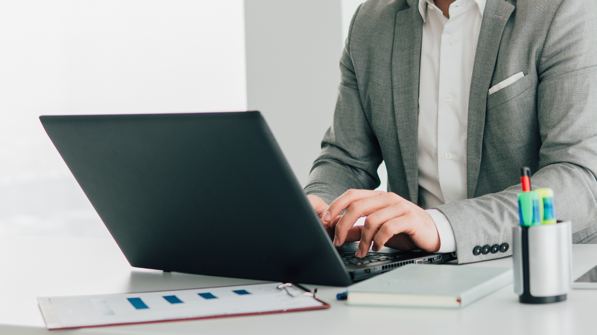 Person in a grey blazer typing on a laptop
