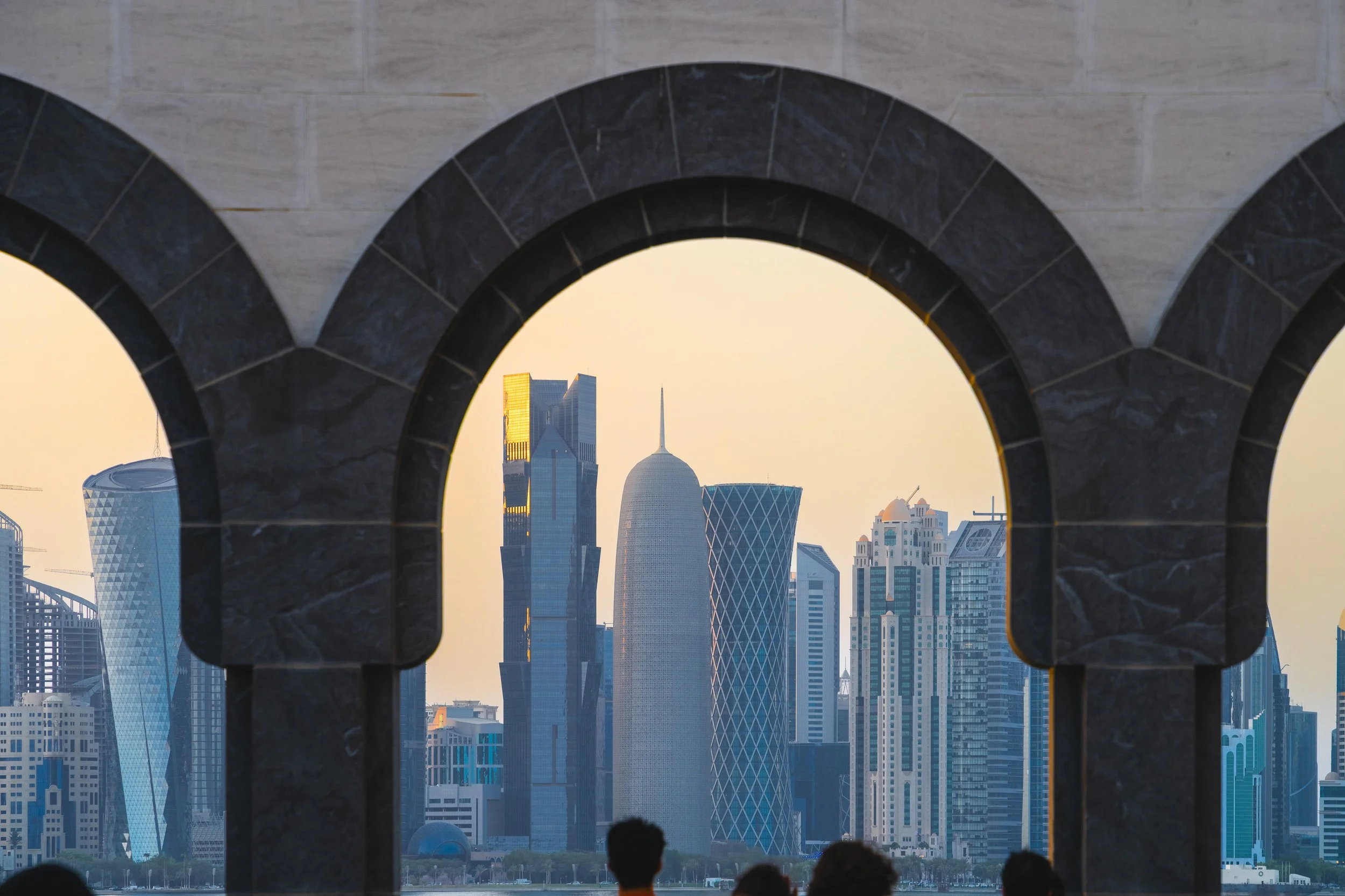 View of modern city skyline through an arched window with stone framing, including skyscrapers such as the Shanghai Tower and the Jin Mao Tower in Shanghai, China.