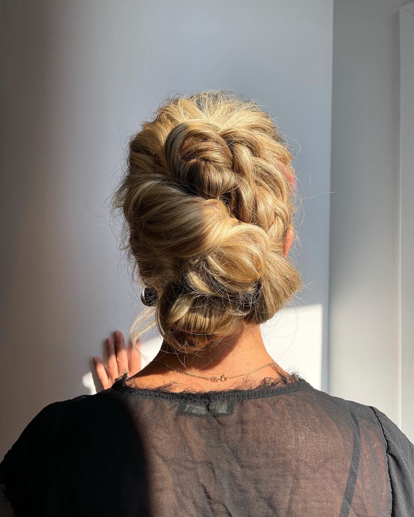Back of a woman with styled blonde hair in a twisted special occasion up do style.