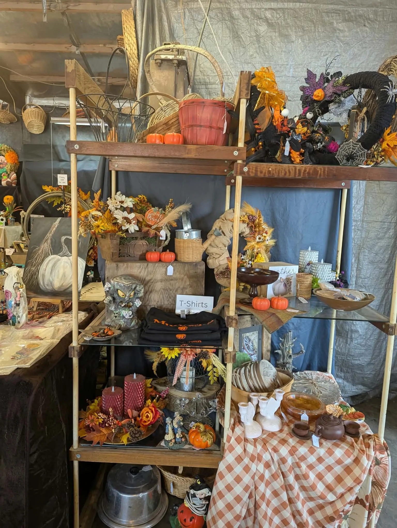 A display of fall-themed home decor and accessories on a multi-level shelving unit, including pumpkins, flowers, wreaths, and small decorative items.