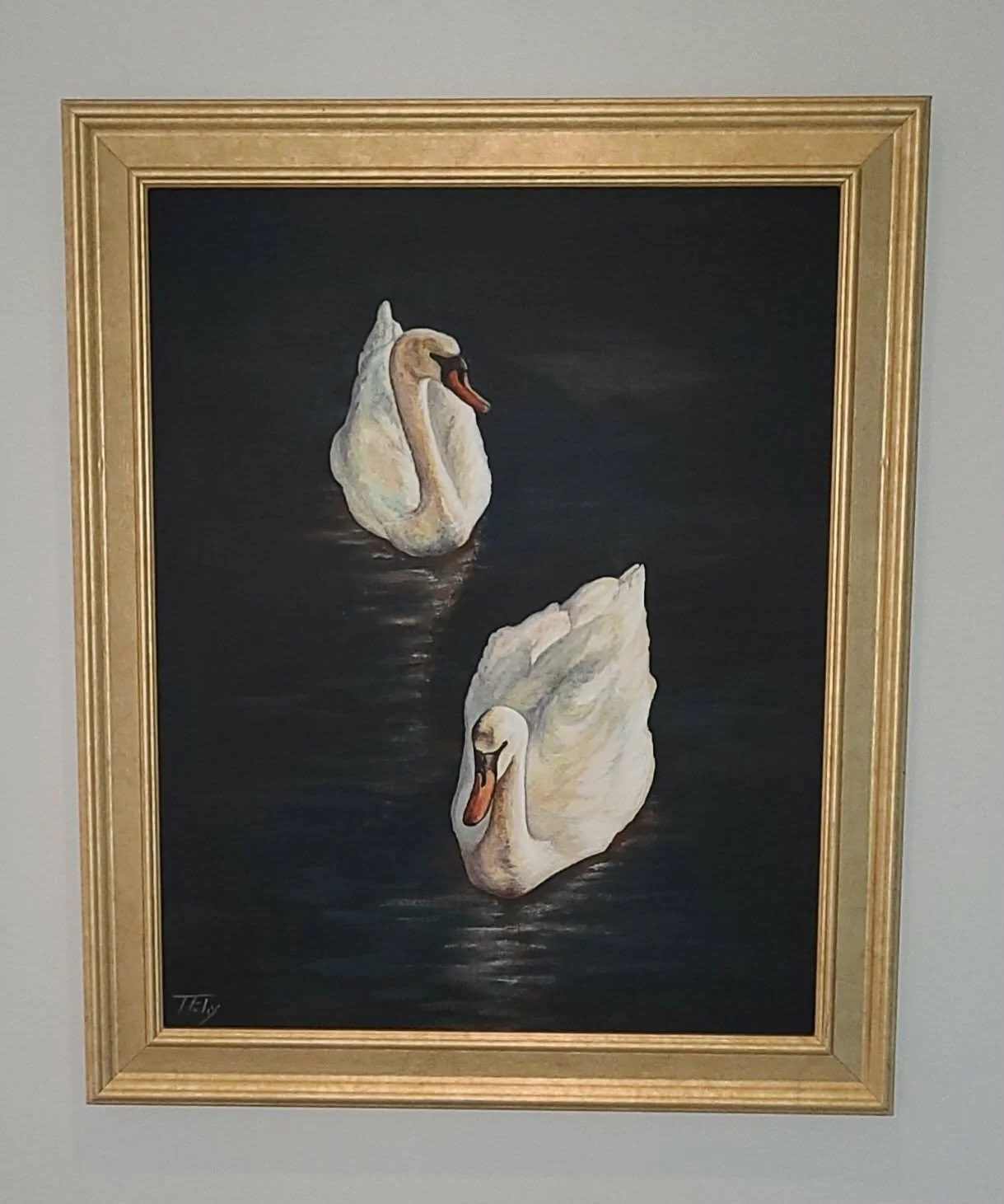 Painting of two white swans swimming on dark water, framed in gold.