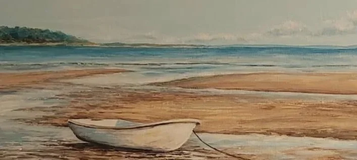 A small white rowboat resting on a sandy beach near the water's edge.