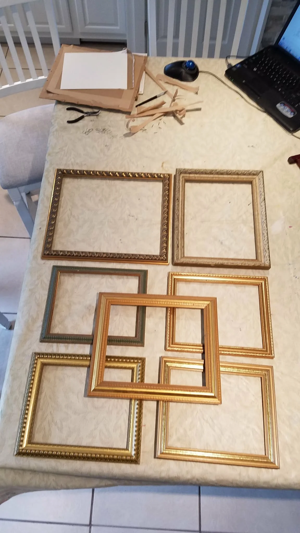 A set of empty picture frames of various sizes and styles arranged on a table with a speckled beige surface.