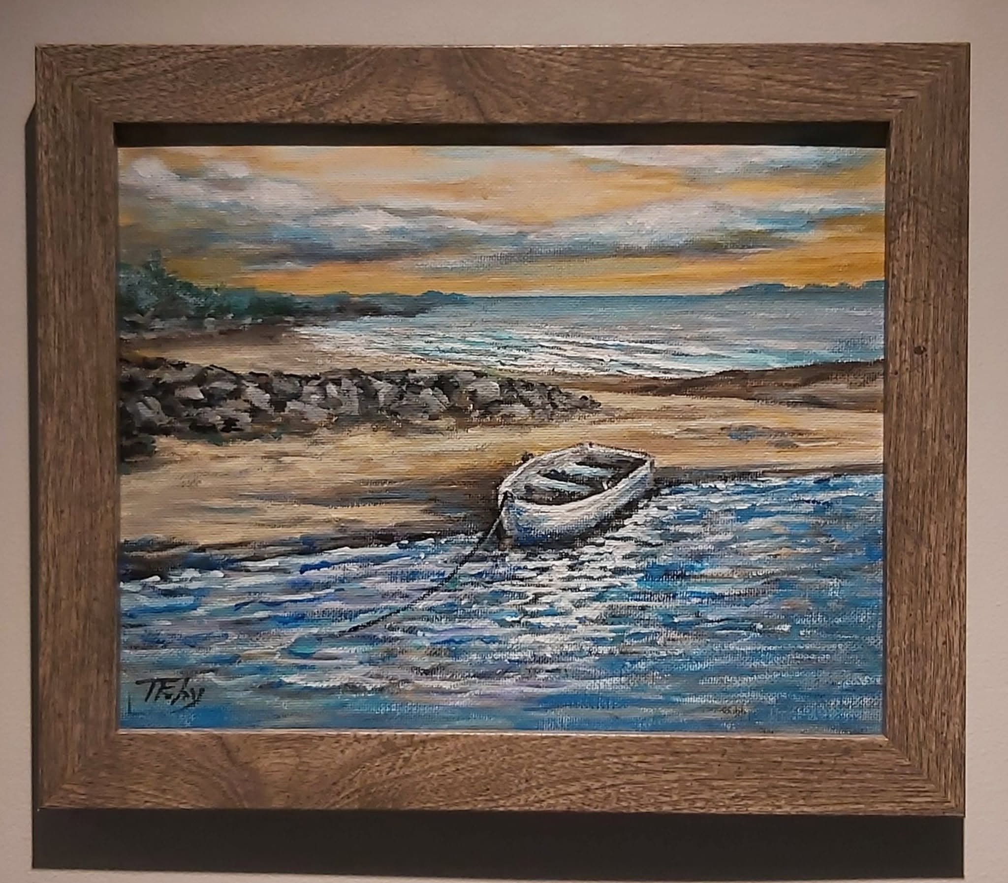 A painting of a seascape with waves crashing on the shore during sunset, framed in a wooden frame.