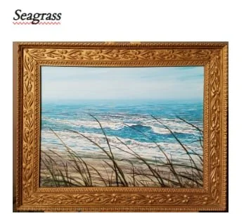 Painting of a beach scene with sand, waves, and grass in a wooden frame