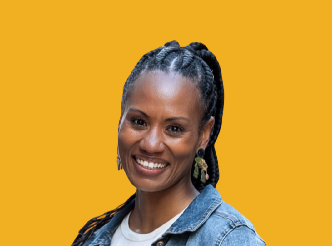 A smiling woman with braided hair, wearing earrings and a denim jacket, against a yellow background.