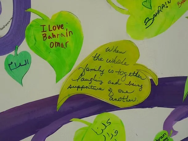 Colorful paper cutouts shaped like leaves with handwritten messages about love and family, connected by purple paper strips.