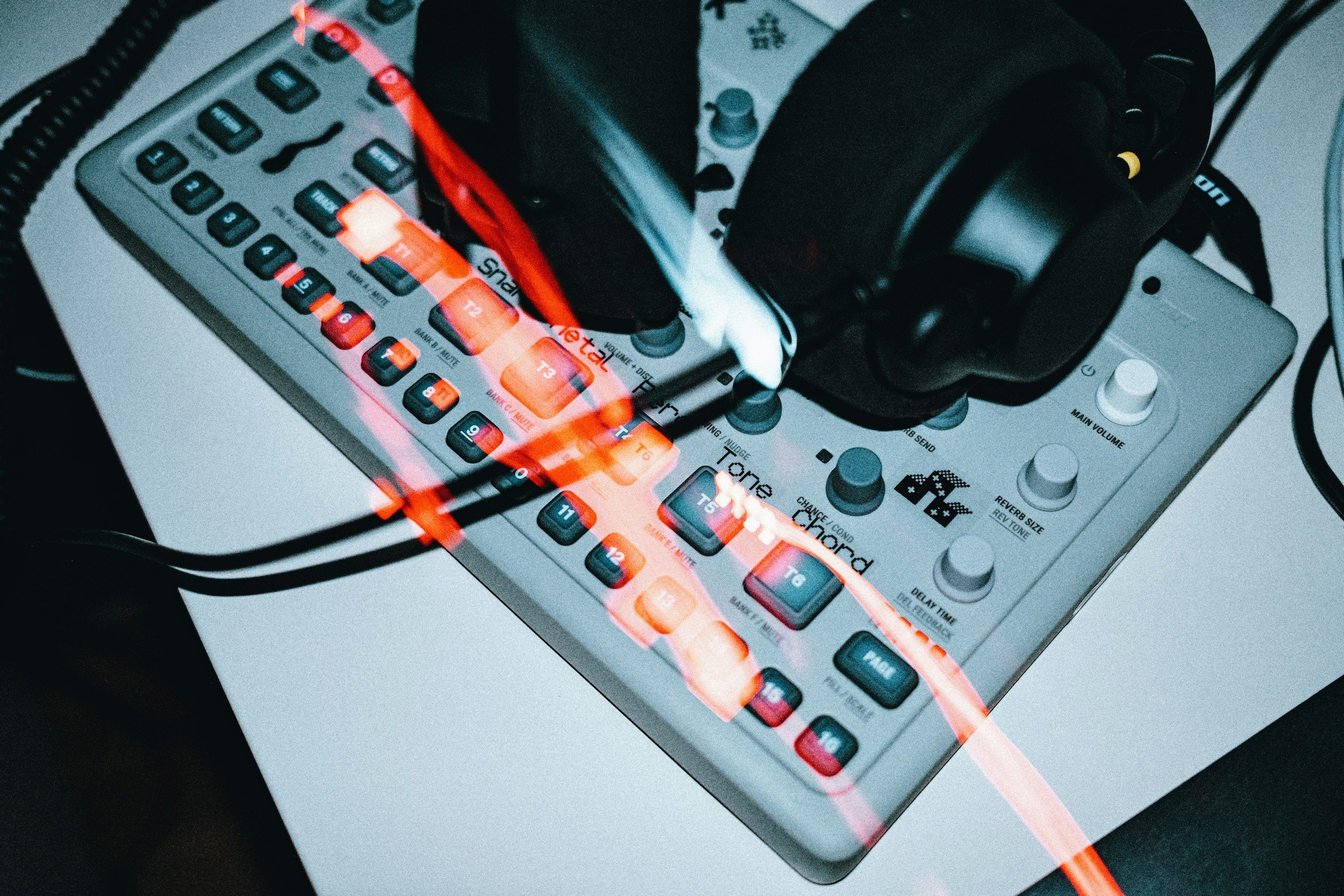 A music production device with glowing orange and red lights, connected to headphones, on a white surface. It is equipment used for TSCM, bug sweeping, looking for listening devices and cameras performing unlawful monitoring.