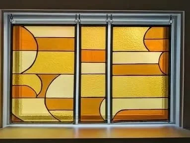 Colorful stained glass window with geometric patterns in orange, yellow, and brown
