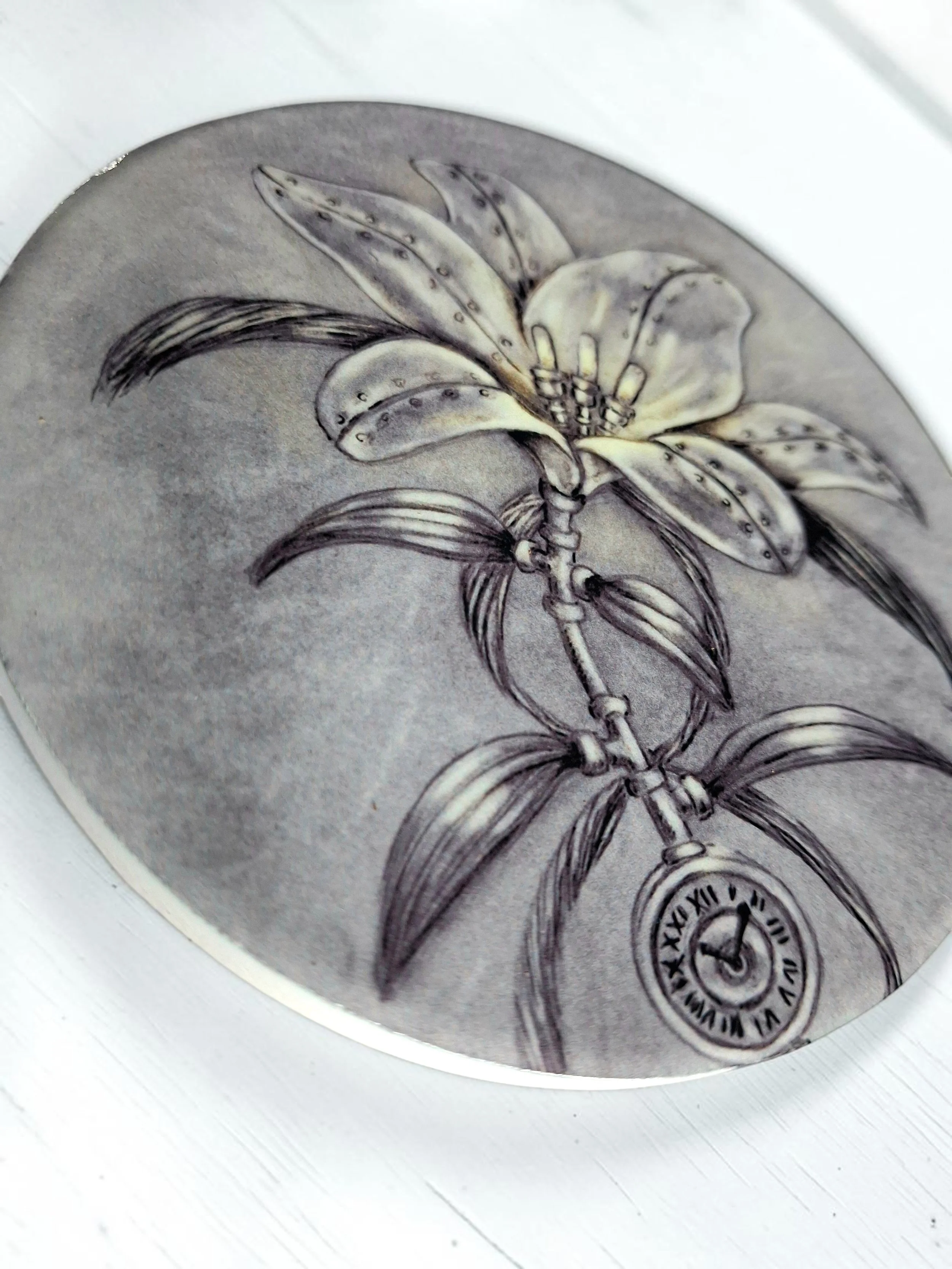 round glossy ceramic coaster flat lay, with hand drawn artwork printed onto it featuring lily flower with a steampunk style