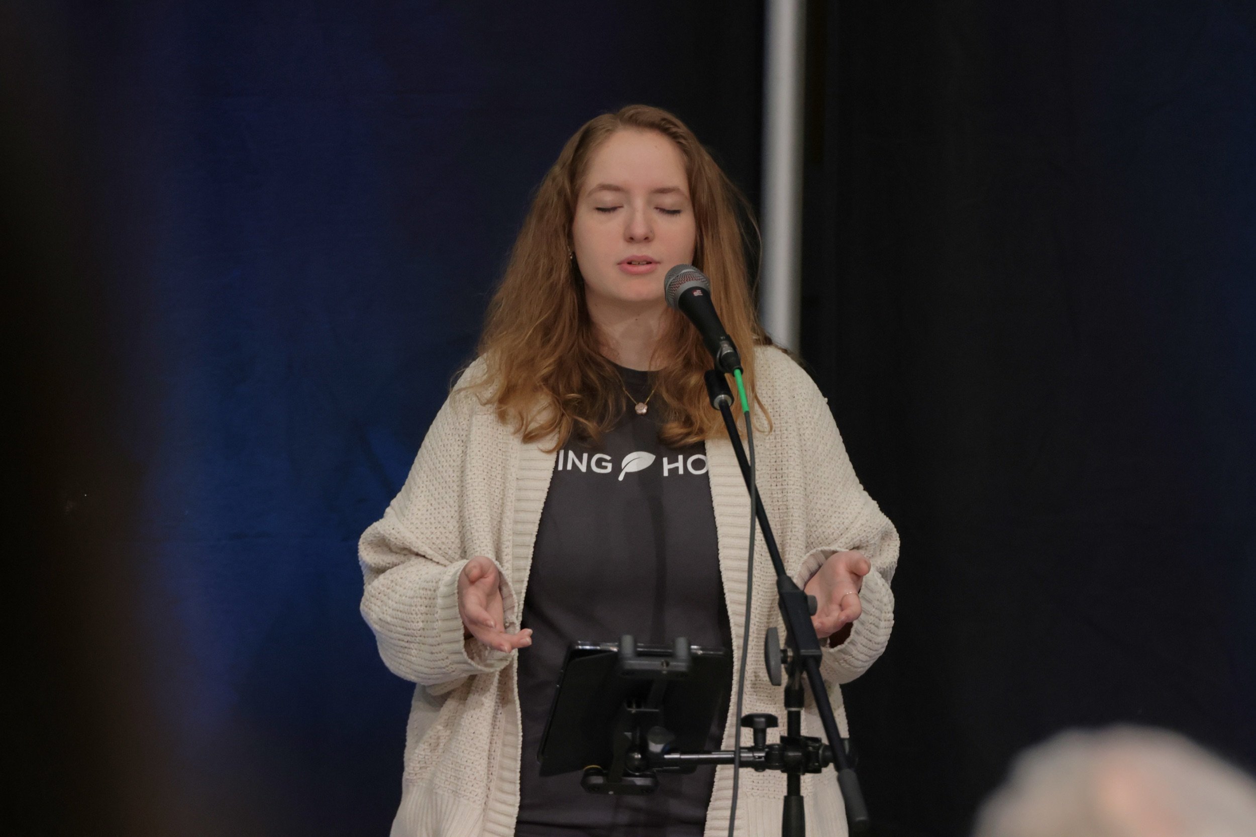 A worship leader in a Living Hope Church shirt sings and prays during a Sunday gathering.