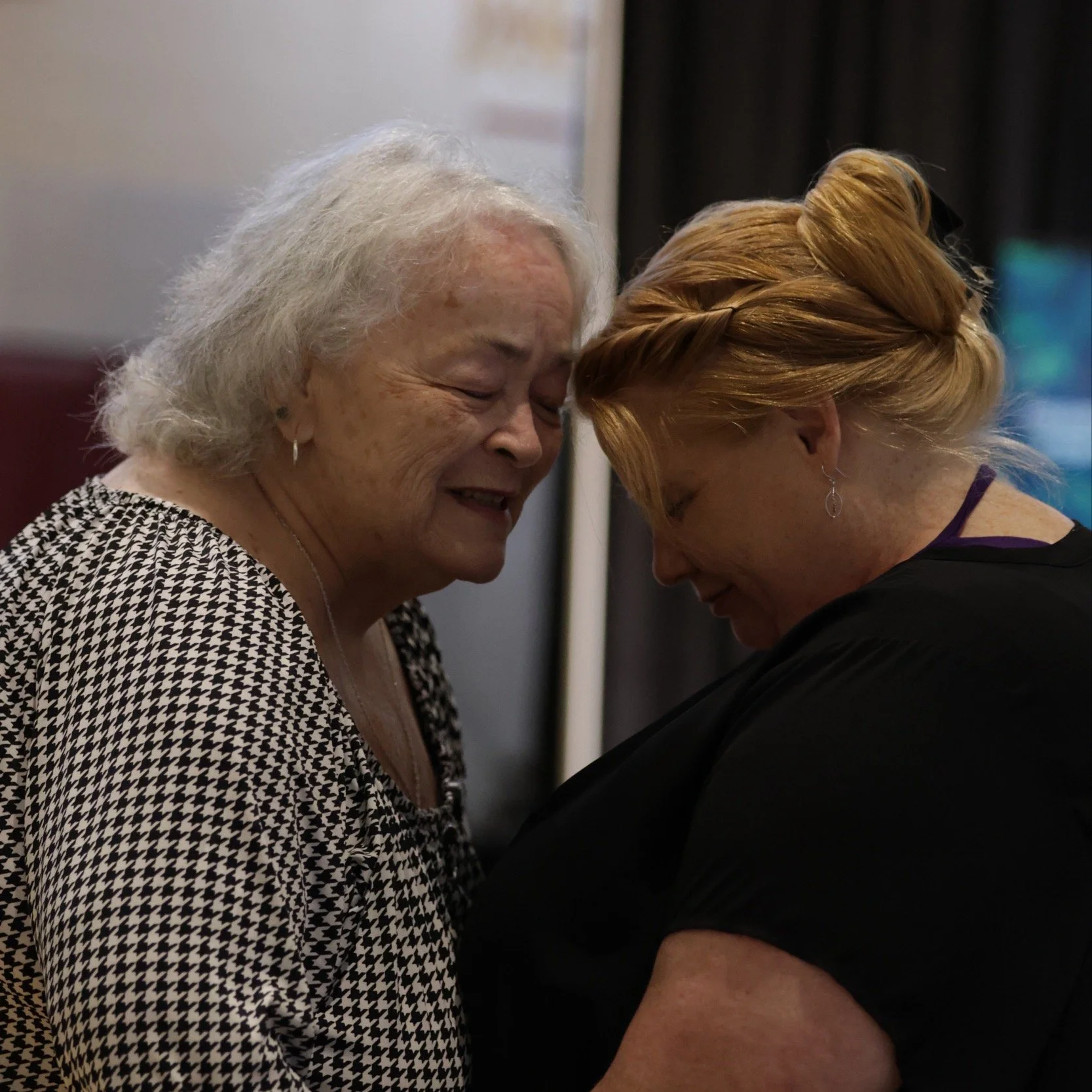 Two women from Living Hope Church lean in close and pray together.