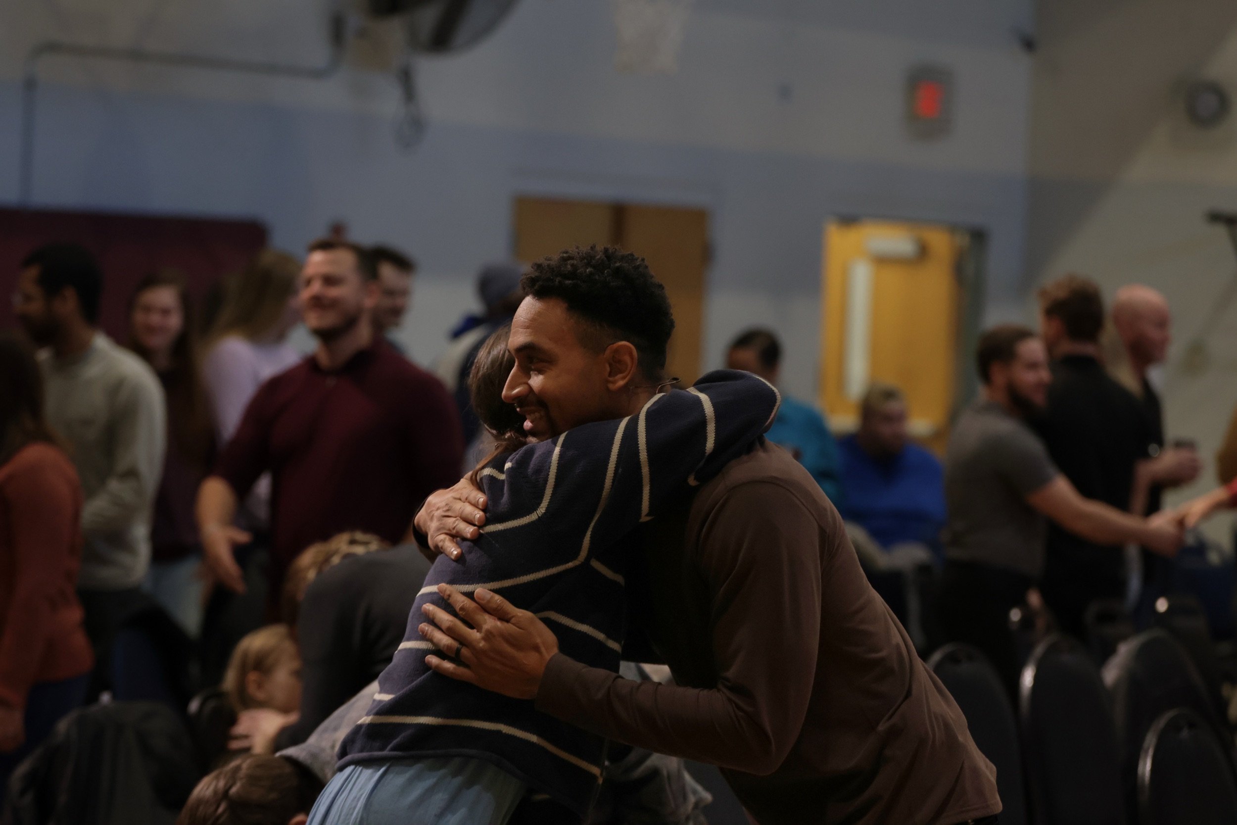 Two friends share a hug as people greet one another at a Living Hope Church gathering.
