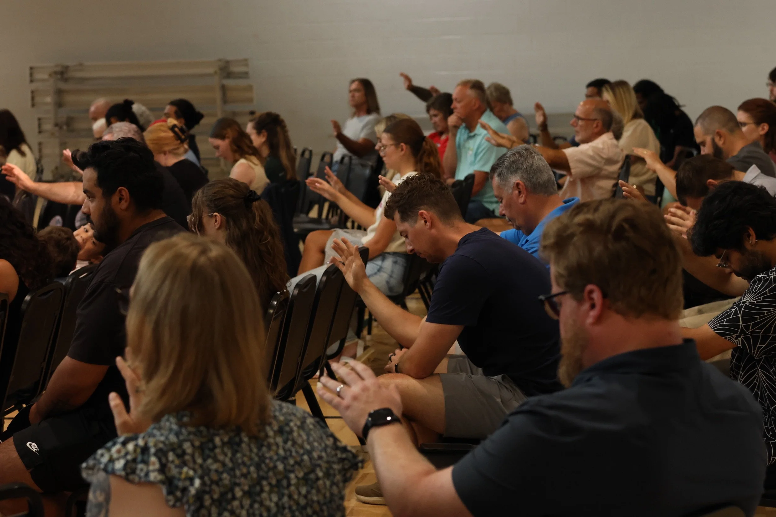 People worship and pray with hands raised during a Sunday gathering at Living Hope Church.