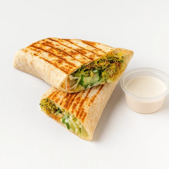 Grilled veggie wrap with lettuce and a side of white dipping sauce in a plastic cup.