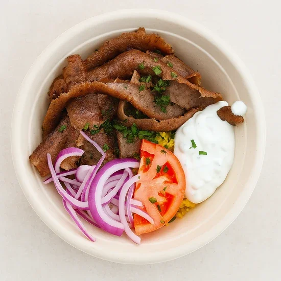 A bowl of Mexican food with grilled steak slices, sliced red onions, a halved tomato, white sauce, and yellow rice garnished with chopped herbs.