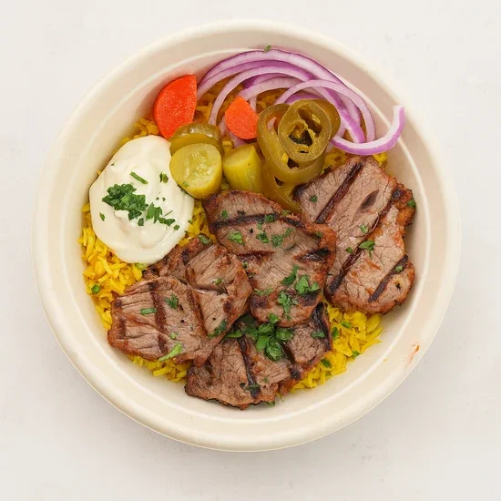 Steak slices with grilled marks served over yellow rice, topped with fresh herbs, accompanied by pickled jalapeños, sliced red onions, carrots, and a dollop of sour cream garnished with parsley in a bowl.