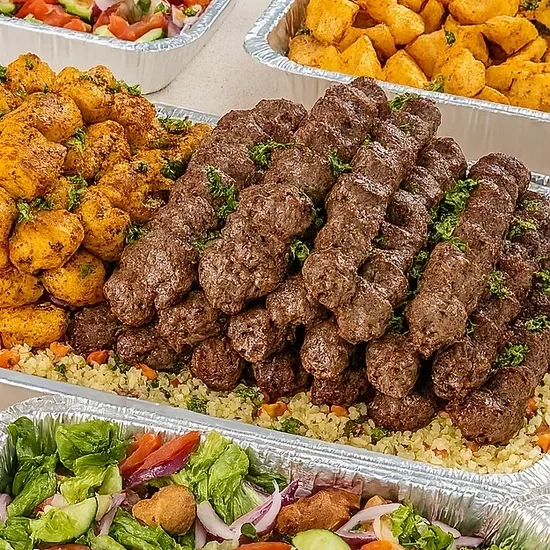 Platters of Middle Eastern-style grilled meat kebabs, falafel, roasted potatoes, and a fresh vegetable salad.