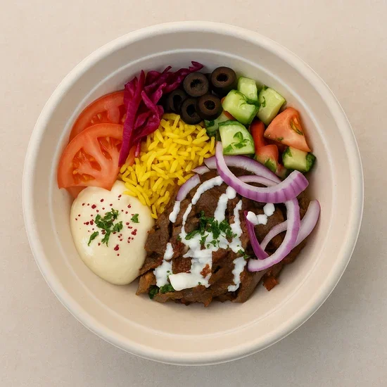 Bowl with tomato slices, shredded purple cabbage, sliced black olives, diced cucumbers, red onion slices, shredded yellow cheese, cooked beef with white sauce and herbs, and a dollop of sour cream garnished with herbs and paprika.