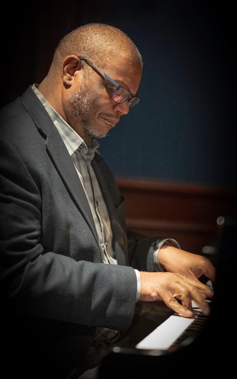 Side profile image of Reggie Thomas playing the piano.