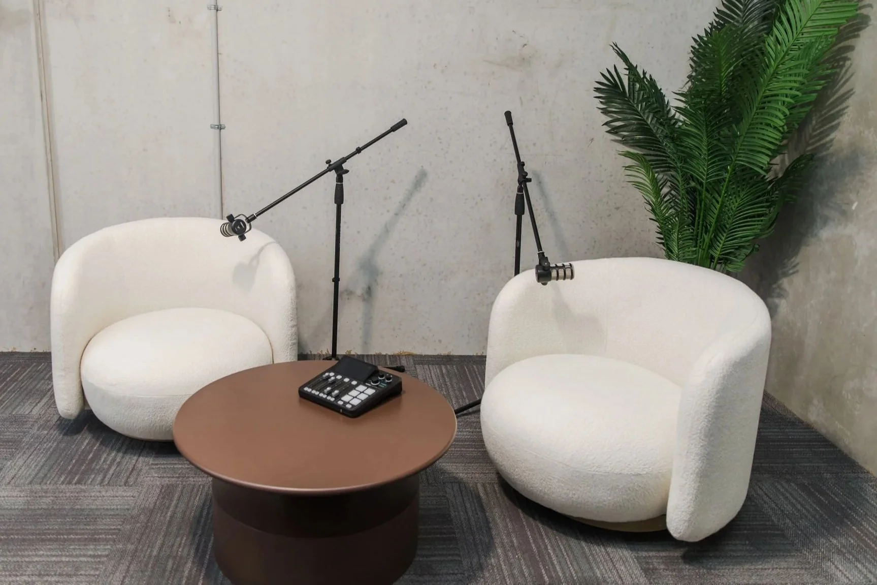 Boucle armchairs, RODE boom mics and a RODECaster Duo, ready to record a relaxed conversation.