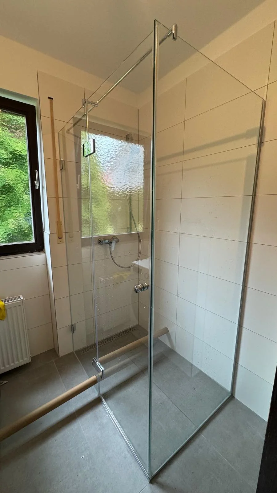 Eine moderne, offene Duschkabine mit Glaswänden in einem Badezimmer.
