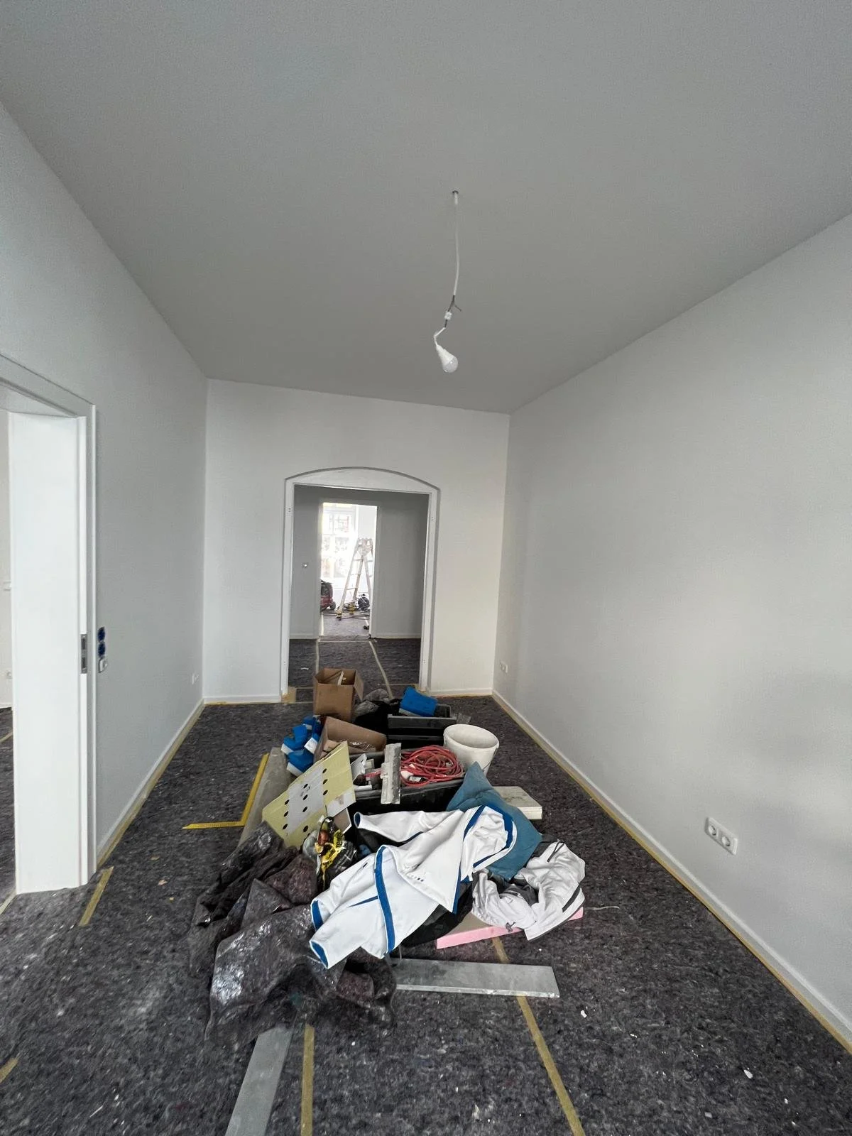 Unaufgeräumter Flur in einem Haus mit Baustellenmaterialien und Anstrichutensilien auf dem Boden