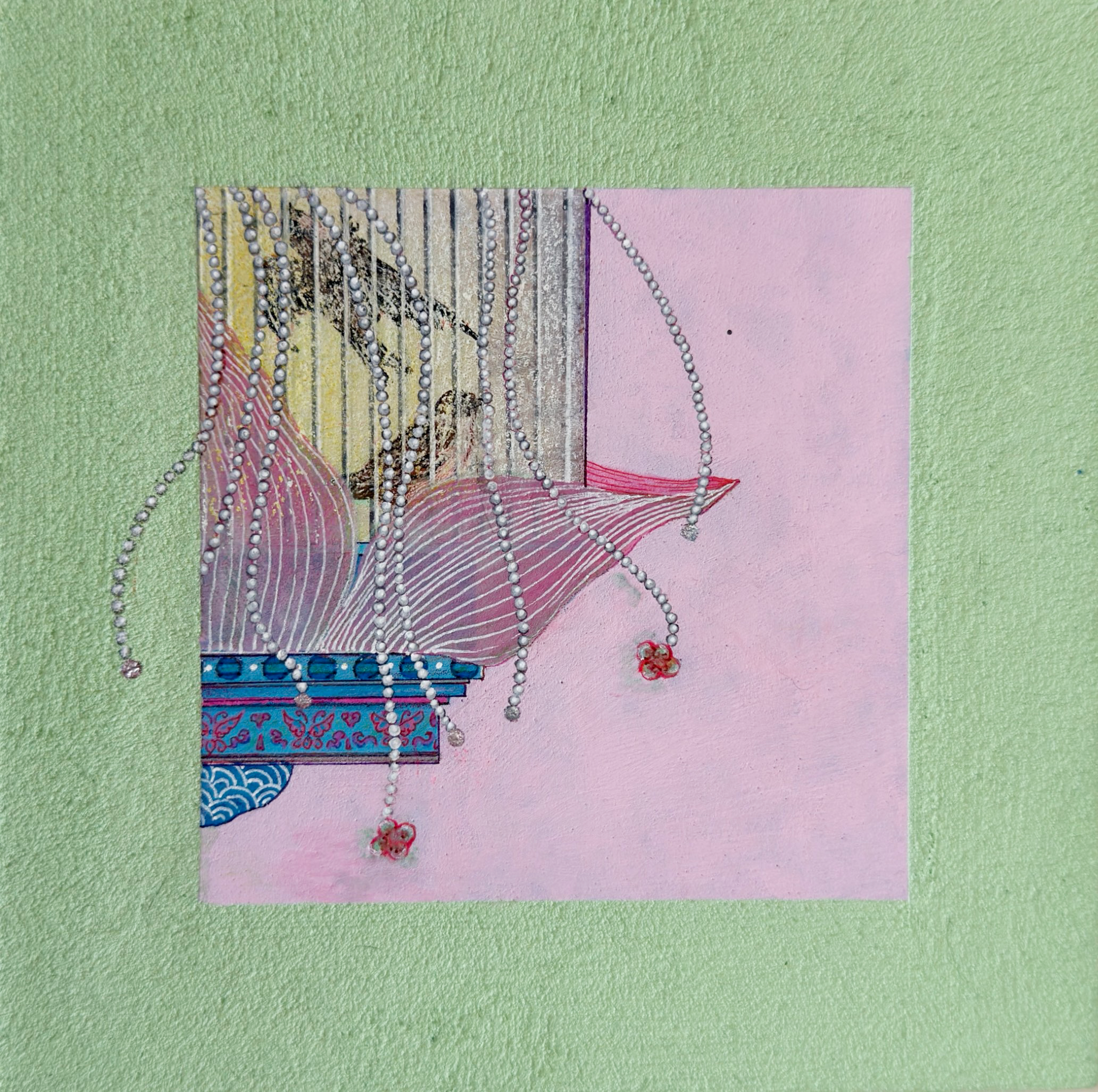 Close-up of a textured green wall with a colorful collage featuring various patterns, materials, and strings of pearls attached to it.