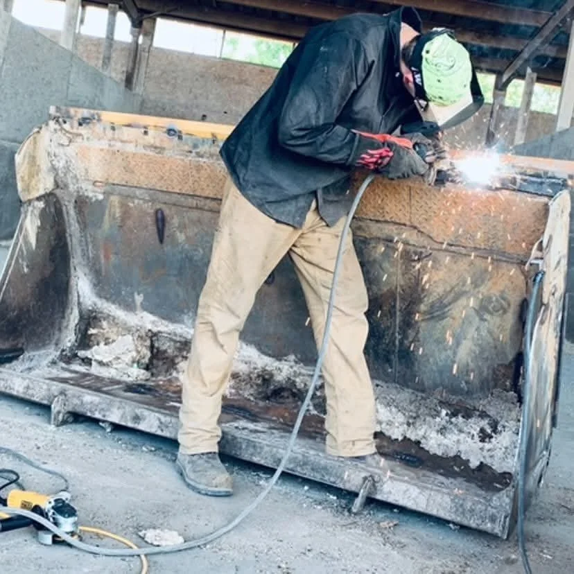 A person welding inside an industrial metal structure with sparks flying from the welding process.