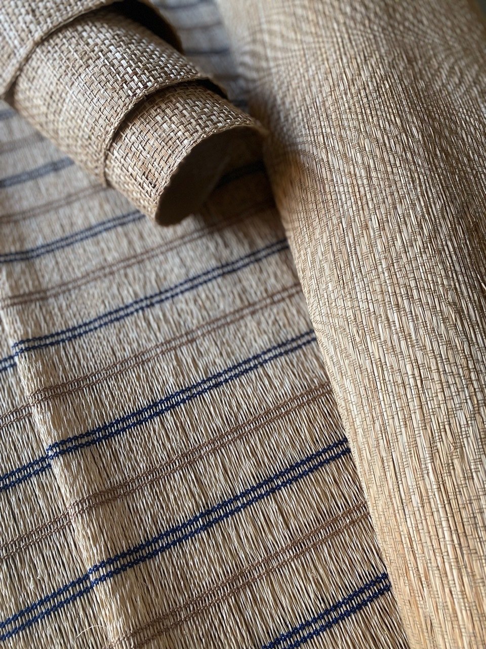 Close-up of woven bamboo mats with a rolled-up piece of similar material on top, showing detailed pattern and texture.