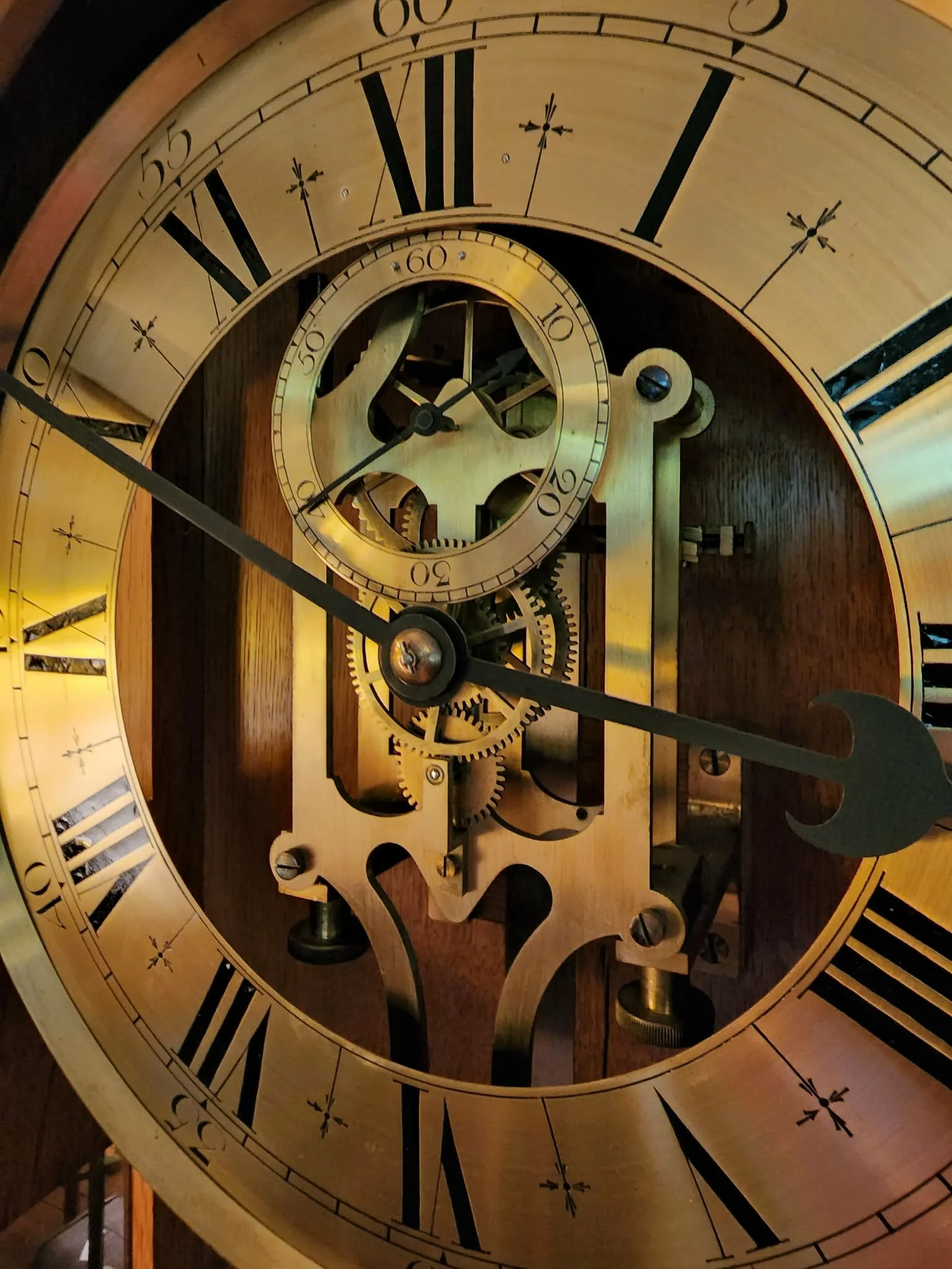 Close-up of an antique clock movement with a Roman-numeral dial and visible gears.