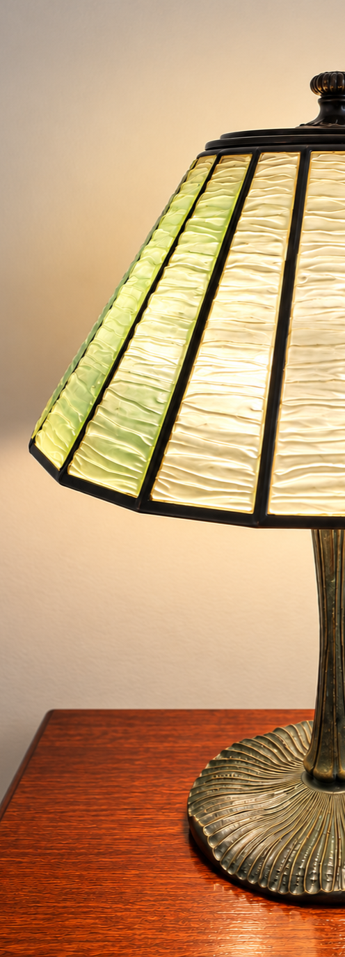Antique Tiffany Studios table lamp with a green glass shade on a wooden table.