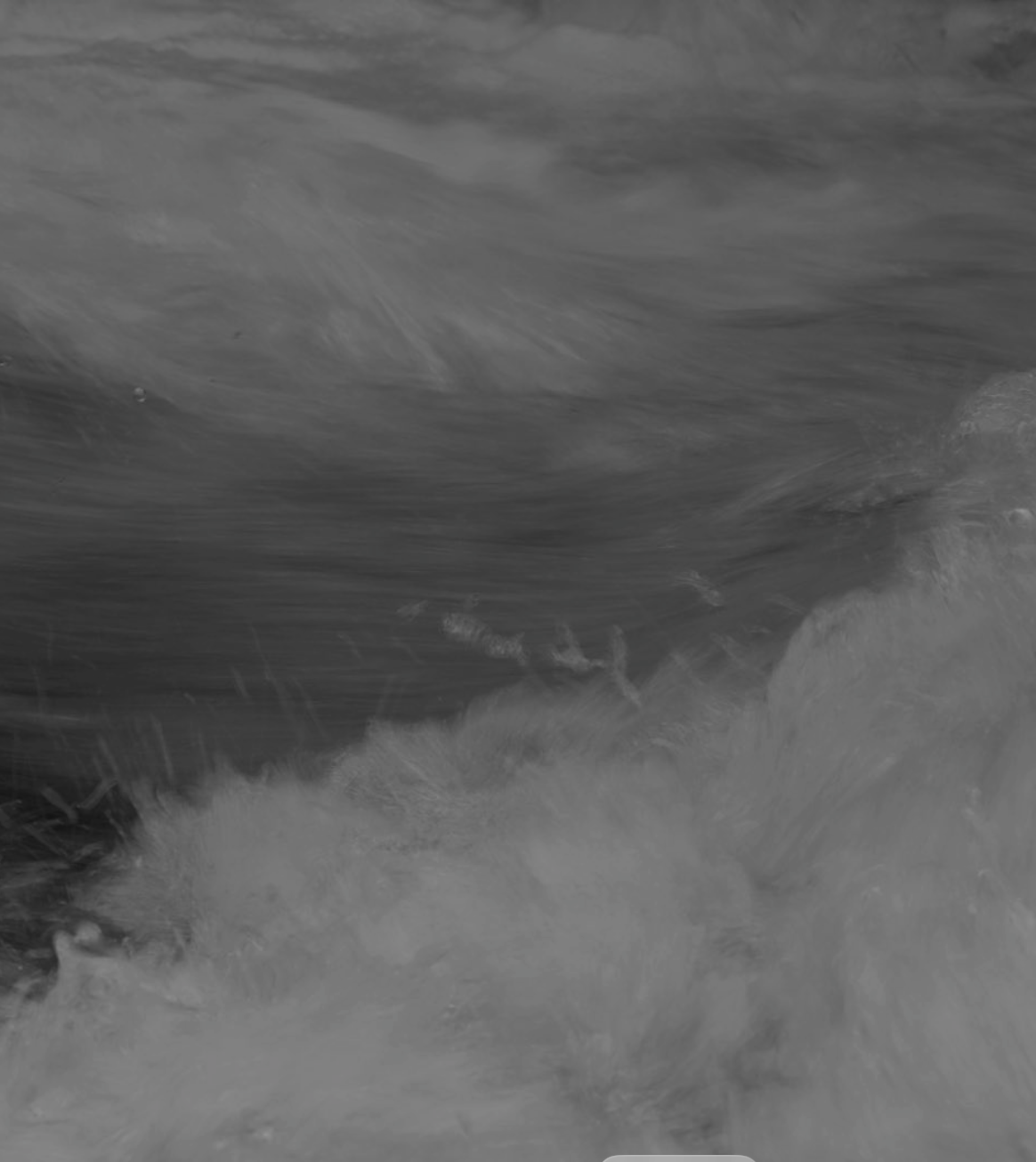 Black and white image of Japanese ocean waves, with visible foam and swirling water.