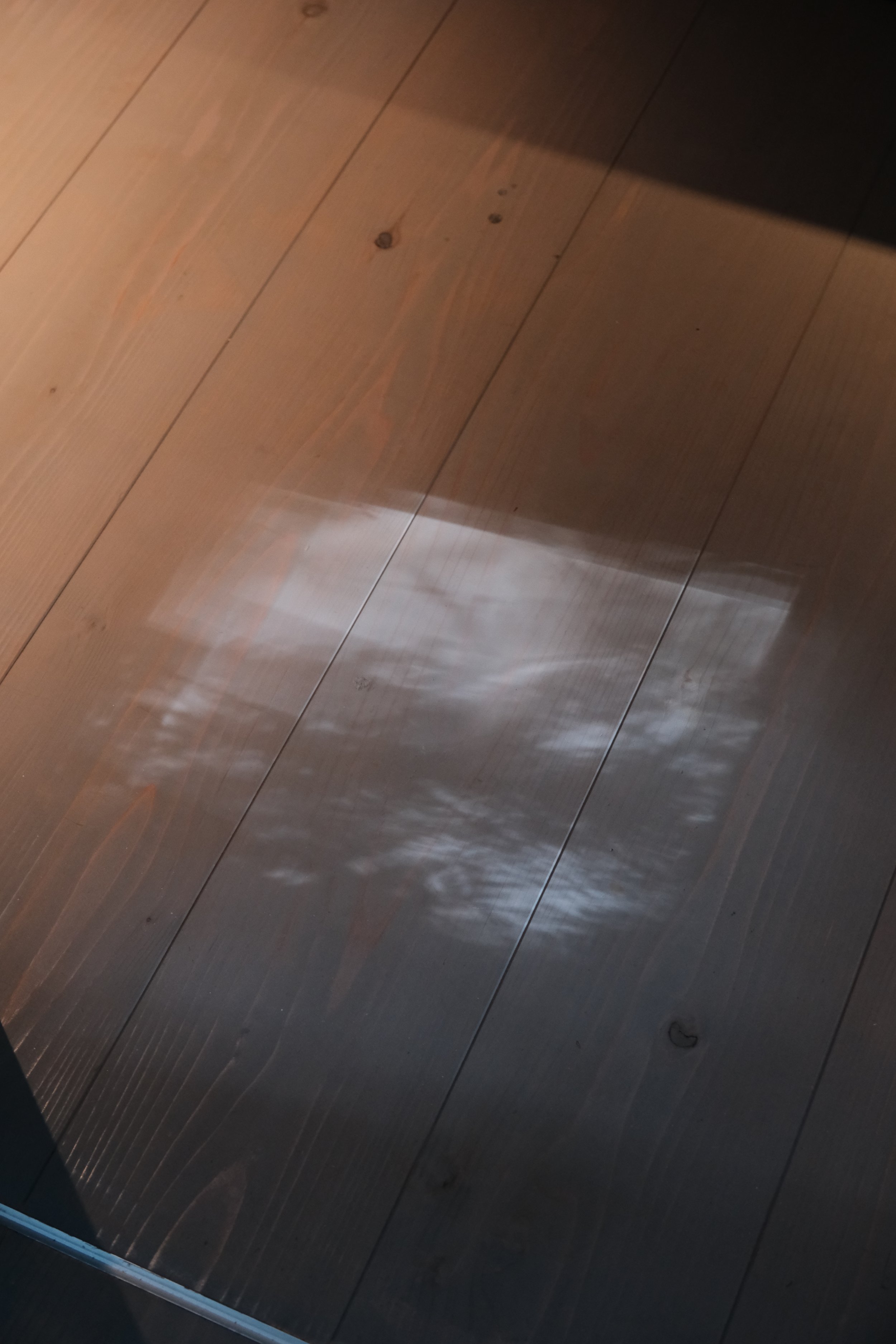 A wooden floor with a Komorebi shadow reflection corner.