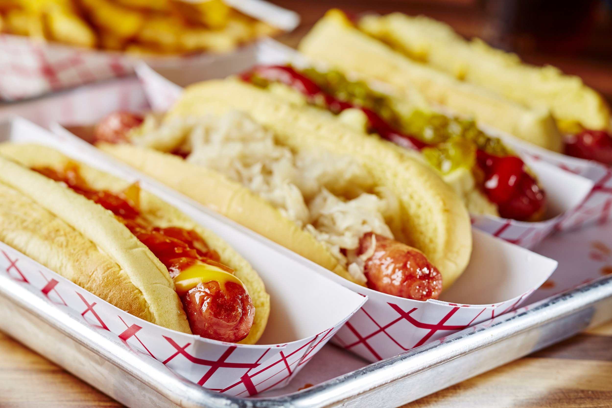 Tray of hot dogs in buns topped with ketchup, mustard, and relish.