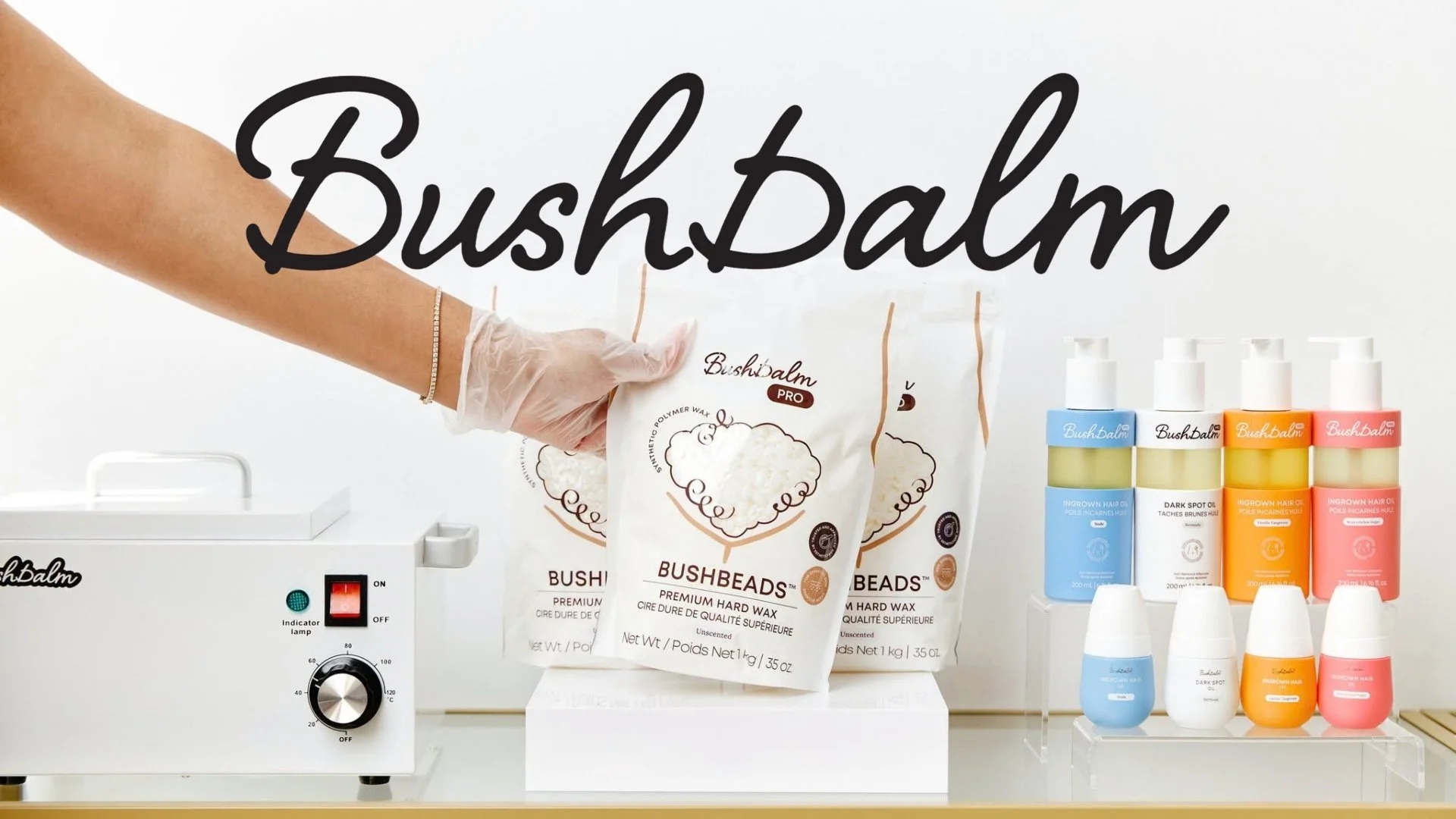 Display of Bush Balm products, including wax and hair oil bottles, with a person's hand holding a bag of Bush Balm wax and a wax machine nearby.