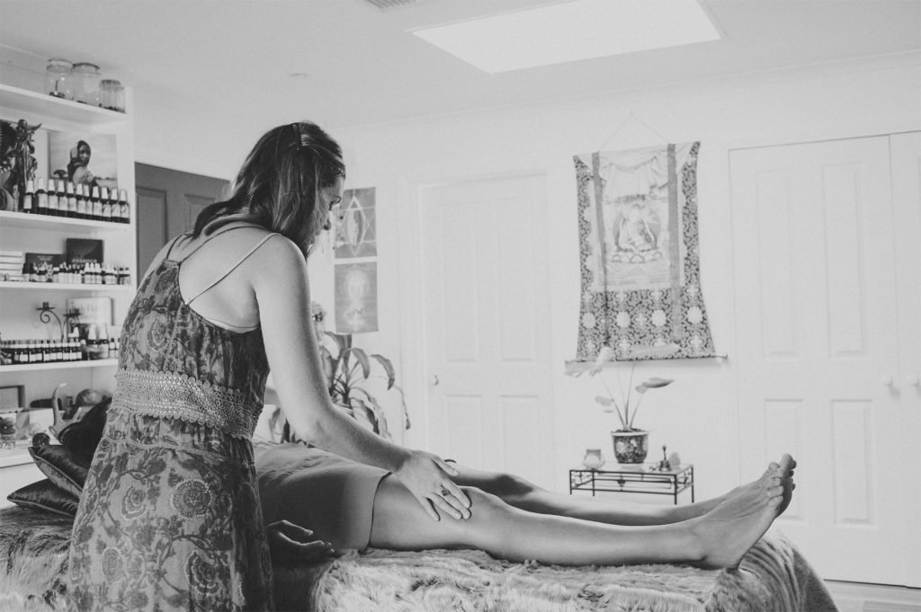 A woman giving a massage to a person lying on a massage table in a cozy room.