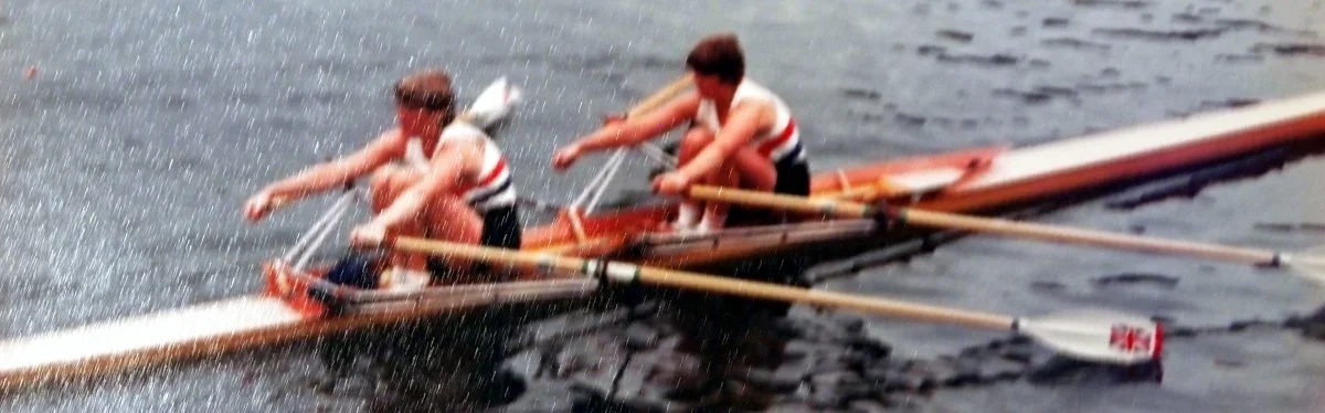 Two rowers in a boat competing on the water during daytime.
