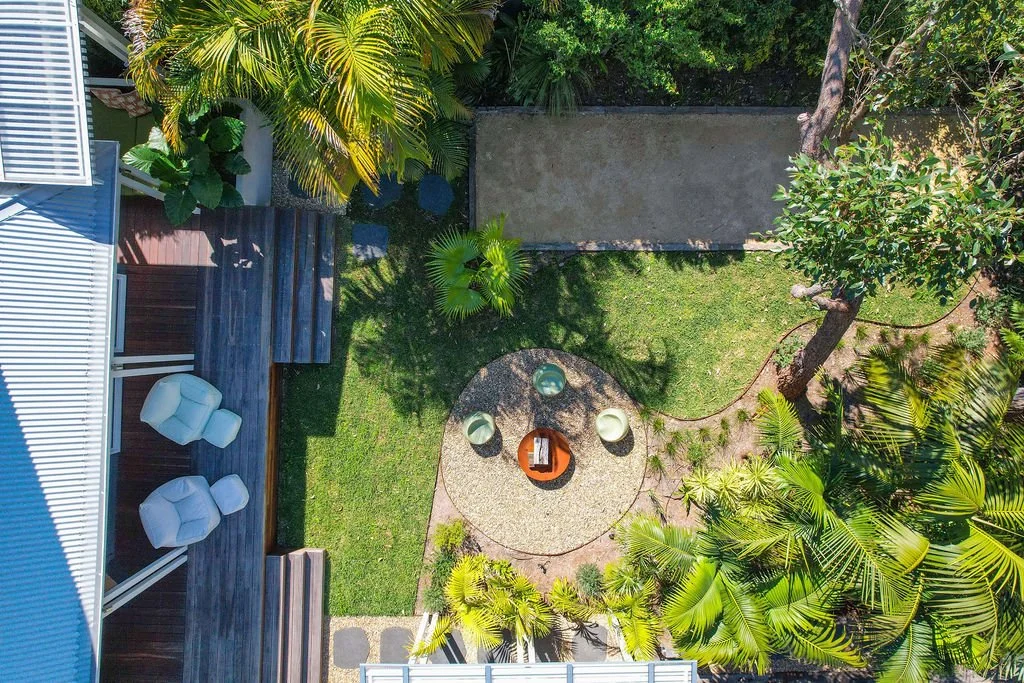 Yaraana Pearl beach holiday Luxury house Diamond road  An aerial view of a backyard with outdoor furniture, trees, and a concrete pathway.