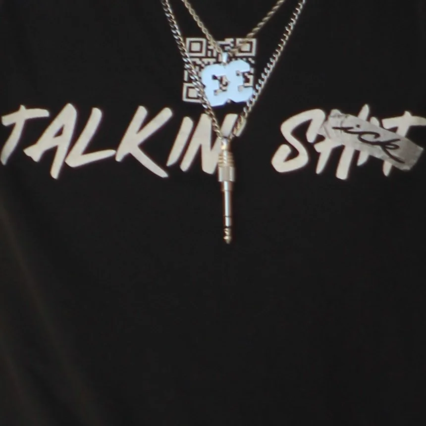 Close-up of layered silver necklaces and pendants over a black graphic T-shirt