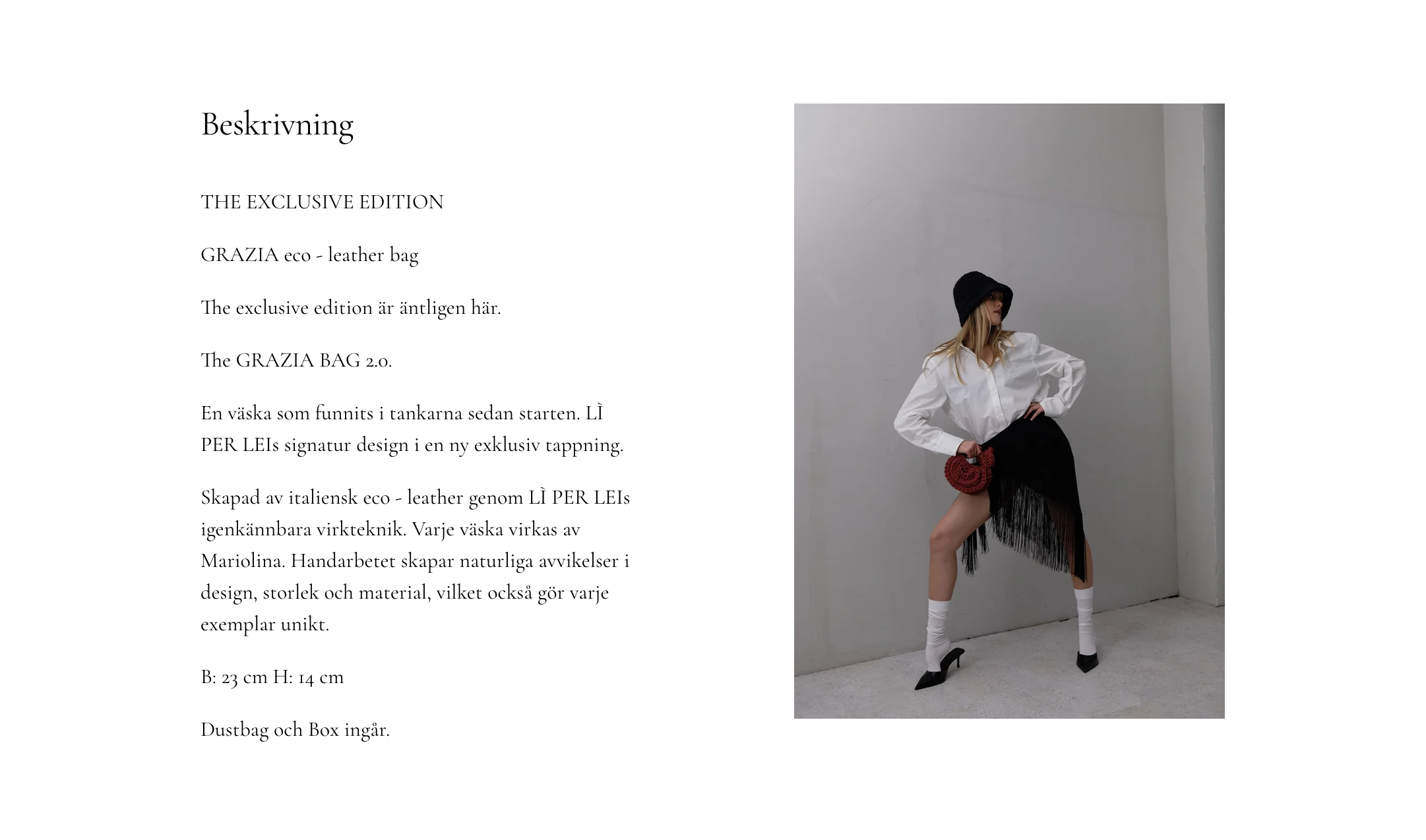 A woman wearing a black wide-brimmed hat, white button-up shirt, black skirt with fringe, white knee-high socks, and black heels, standing against a plain white wall in a minimalist setting.
