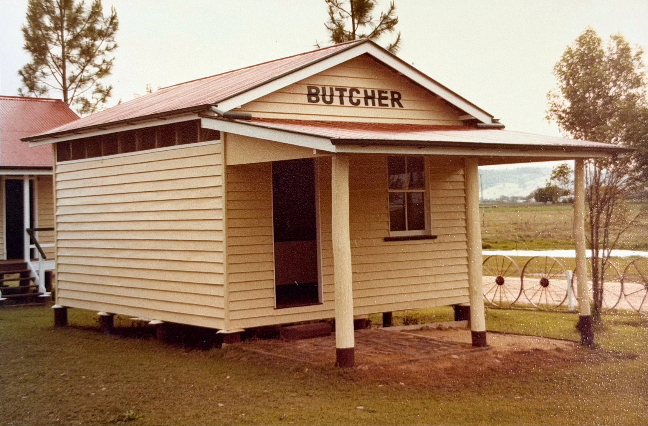 A small wooden building labeled 'Butcher' with a metal roof and surrounding trees.