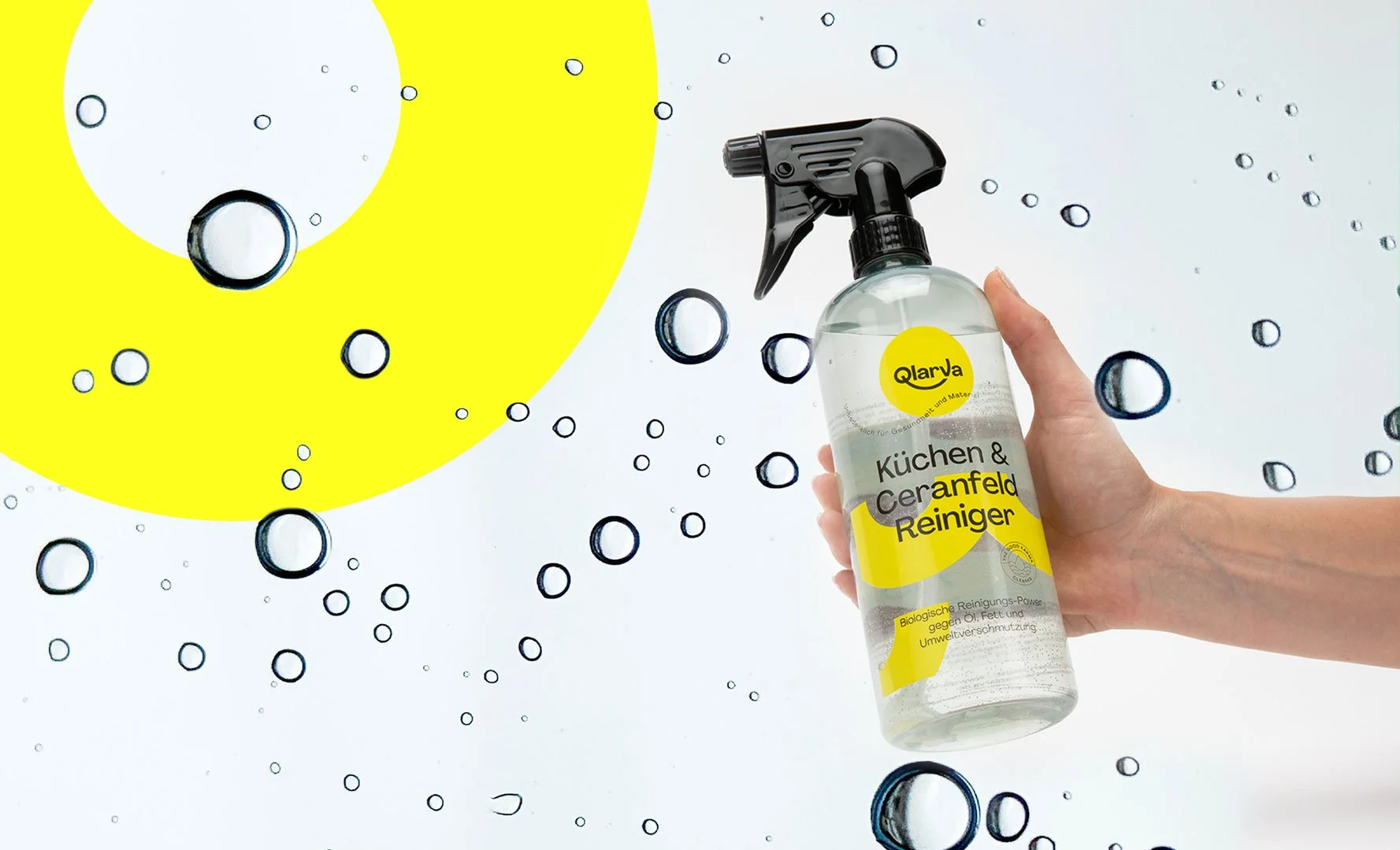 Hand hält eine Flasche mit Reinigungsspray vor einem weißen Hintergrund mit schwarzen und gelben Kreisen, die an Wasserbläschen erinnern, die das Produkt auf der Oberfläche verteilt.
